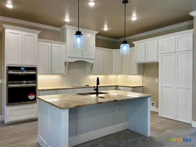 kitchen with decorative light fixtures, light stone counters, and white cabinetry