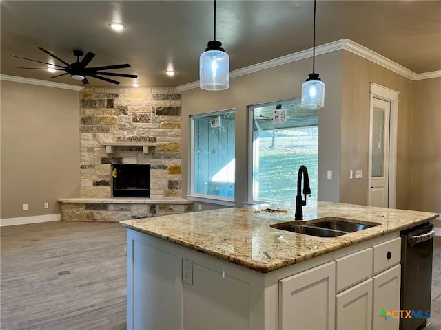 kitchen featuring light stone counters, white cabinetry, hanging light fixtures, and sink