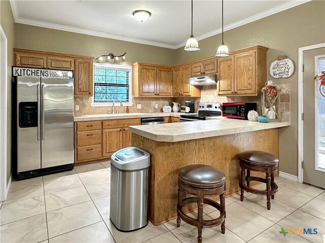 kitchen featuring crown molding, backsplash, appliances with stainless steel finishes, sink, and a breakfast bar area