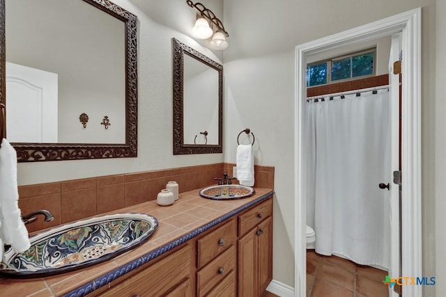 full bathroom with double vanity, tile patterned flooring, and toilet