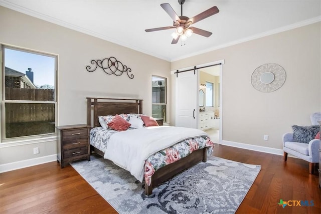 bedroom with dark hardwood / wood-style flooring, a barn door, crown molding, and ensuite bath