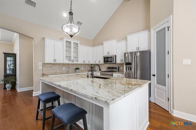 kitchen featuring sink, light stone counters, high end appliances, white cabinetry, and pendant lighting