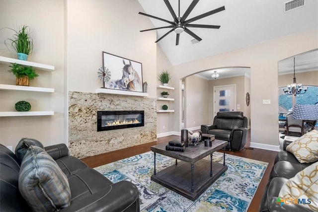 living room featuring a premium fireplace, built in features, high vaulted ceiling, dark hardwood / wood-style floors, and ceiling fan with notable chandelier