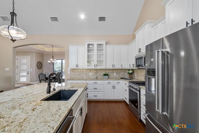4012 Turning Leaf Dr, Nolanville, TX 76559 - kitchen featuring stainless steel appliances, a sink, white cabinetry, arched walkways, and tasteful backsplash
