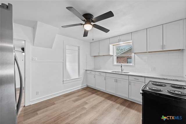 kitchen with backsplash, light wood-style floors, white cabinetry, a ceiling fan, and a sink