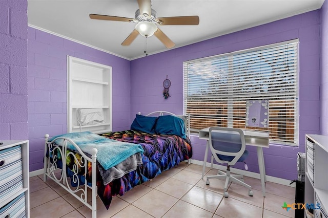 bedroom with light tile patterned floors, concrete block wall, ceiling fan, and ornamental molding