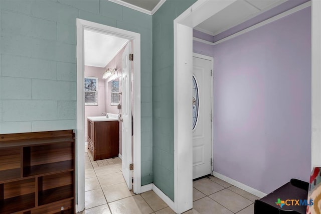 entrance foyer featuring light tile patterned floors, crown molding, and baseboards