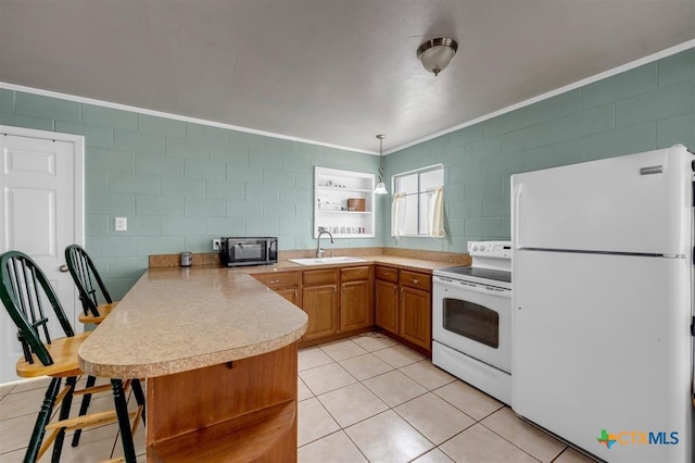 kitchen with a sink, white appliances, a peninsula, light countertops, and light tile patterned floors