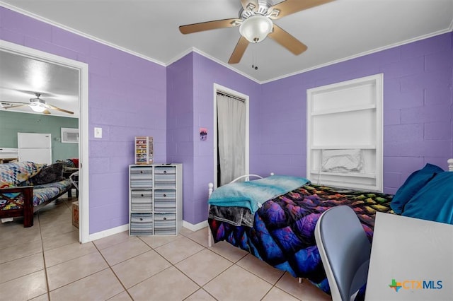 bedroom with a closet, light tile patterned flooring, crown molding, and freestanding refrigerator