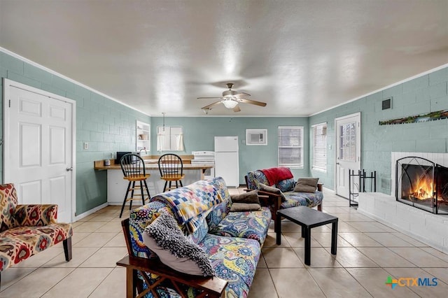 living area with visible vents, ornamental molding, light tile patterned flooring, a fireplace, and ceiling fan