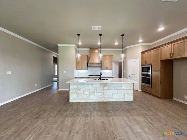 6132 Messina Dr, Temple, TX 76502 - kitchen with premium range hood, appliances with stainless steel finishes, an island with sink, wood finished floors, and ornamental molding