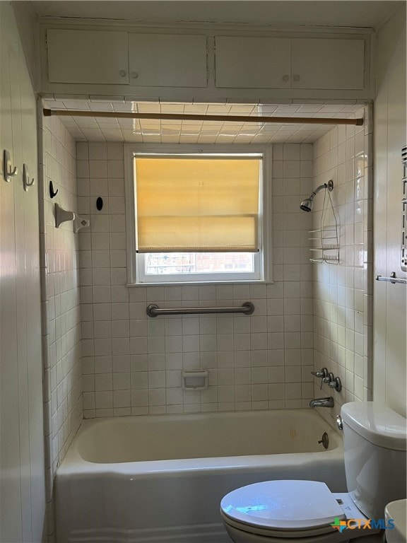 bathroom featuring toilet and tiled shower / bath