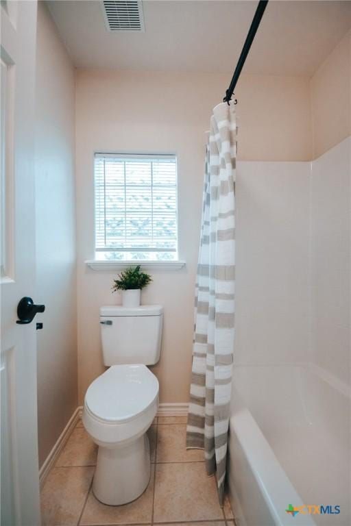 bathroom featuring toilet, visible vents, baseboards, tile patterned floors, and shower / bath combo