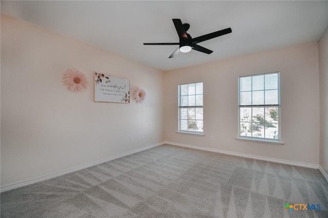 carpeted spare room with a ceiling fan and baseboards