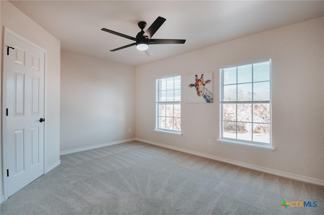 carpeted spare room featuring ceiling fan and baseboards