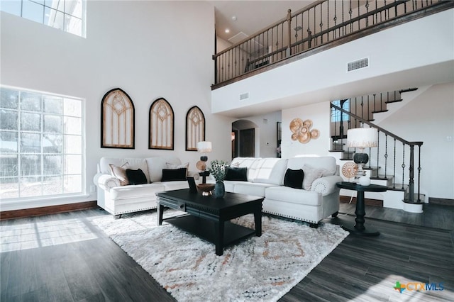 living area with arched walkways, stairway, wood finished floors, and a healthy amount of sunlight