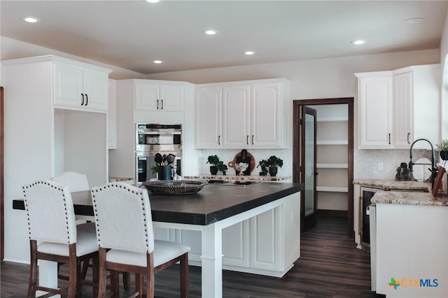 kitchen featuring a sink, white cabinetry, dark wood-type flooring, and stainless steel double oven