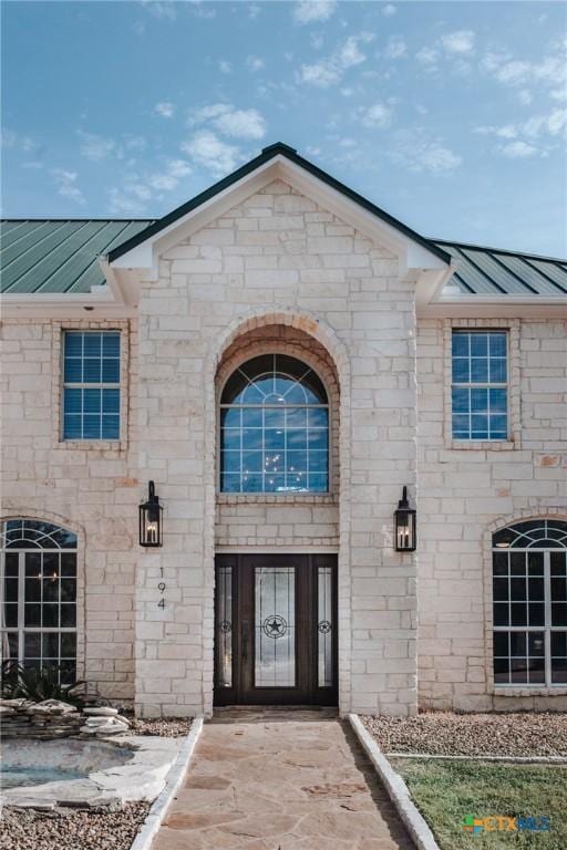 property entrance with stone siding, a standing seam roof, and metal roof