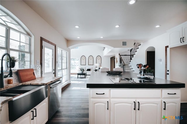 kitchen featuring arched walkways, black electric cooktop, visible vents, open floor plan, and dishwasher