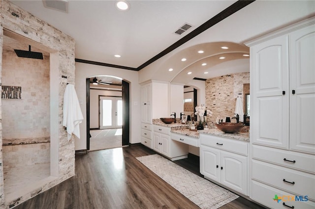 bathroom with wood finished floors, vanity, visible vents, walk in shower, and crown molding