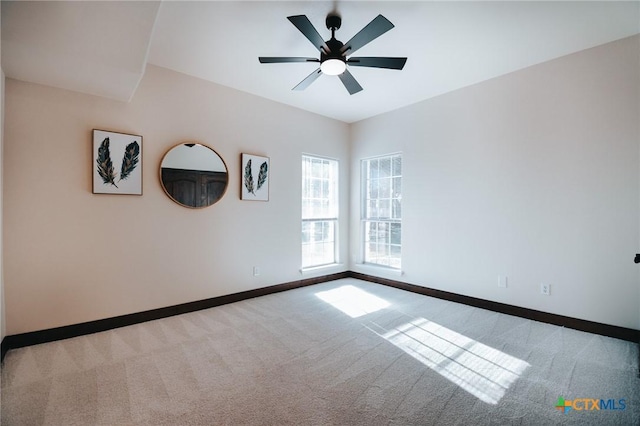 carpeted spare room with ceiling fan and baseboards