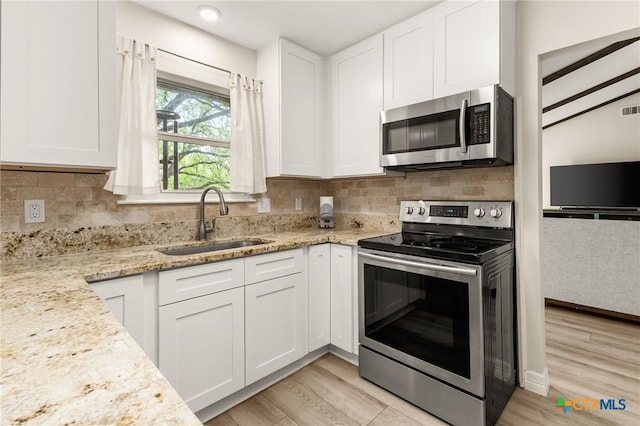 15118 Circle Oak St, San Antonio, TX 78232 - kitchen with stainless steel appliances, a sink, white cabinetry, and light wood-style flooring