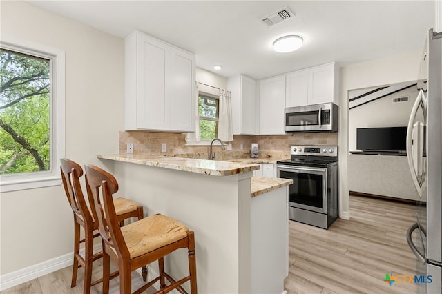 15118 Circle Oak St, San Antonio, TX 78232 - kitchen with stainless steel appliances, a kitchen bar, white cabinets, and light stone countertops