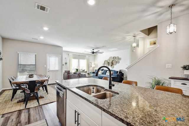 31696 Bard Ln, Bulverde, TX 78163 - kitchen with a sink, stainless steel dishwasher, white cabinetry, wood finished floors, and dark stone countertops