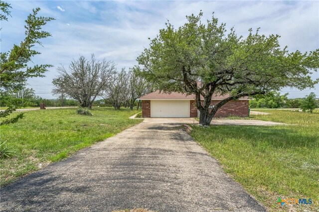 3302 Colorado Dr, Copperas Cove, TX 76522 - obstructed view of property featuring asphalt driveway, brick siding, an attached garage, and a front yard