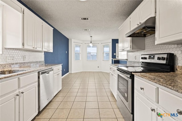 kitchen with a textured ceiling, stainless steel appliances, light tile patterned flooring, and white cabinets