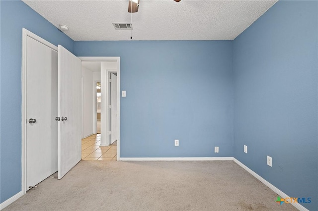 unfurnished bedroom featuring ceiling fan, light carpet, and a textured ceiling