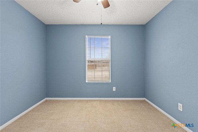 empty room featuring ceiling fan, light colored carpet, and a textured ceiling