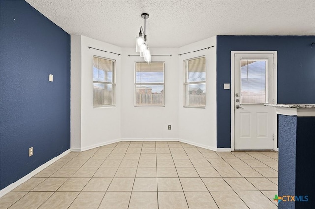 unfurnished dining area with a textured ceiling, a wealth of natural light, and light tile patterned flooring