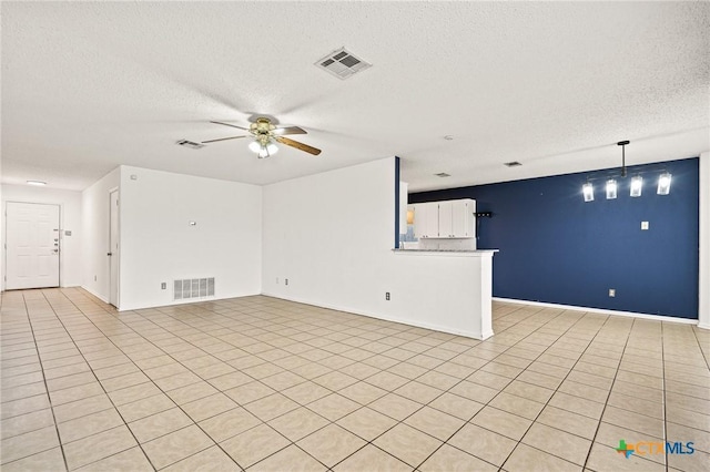 unfurnished living room featuring ceiling fan, a textured ceiling, and light tile patterned floors