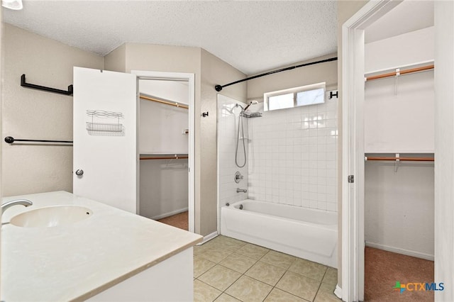 bathroom with tiled shower / bath combo, tile patterned flooring, vanity, and a textured ceiling