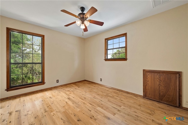 empty room featuring ceiling fan, light hardwood / wood-style flooring, and a healthy amount of sunlight