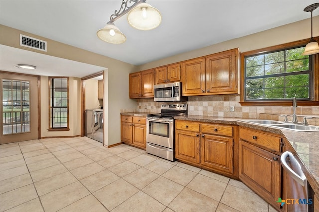 kitchen featuring pendant lighting, appliances with stainless steel finishes, sink, backsplash, and light tile patterned flooring