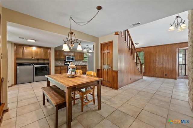 tiled dining area featuring wooden walls and washing machine and clothes dryer