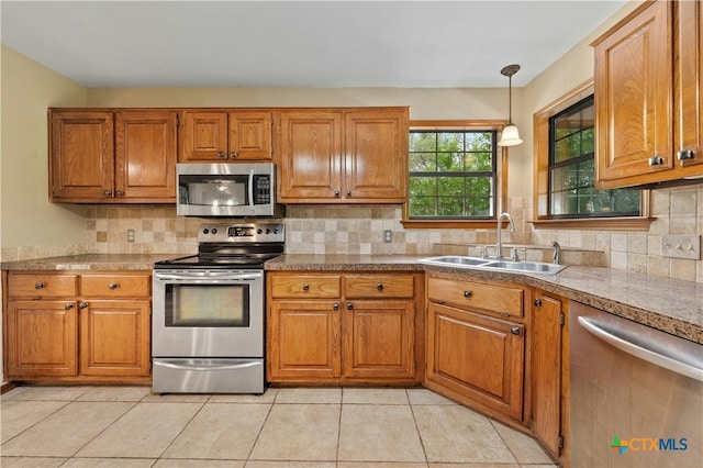 kitchen featuring pendant lighting, appliances with stainless steel finishes, decorative backsplash, sink, and light tile patterned floors