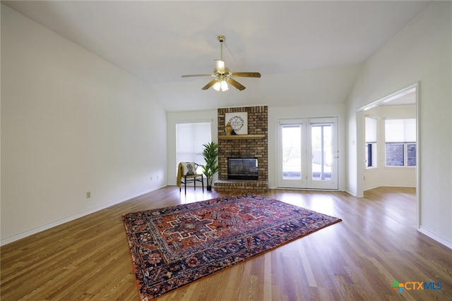 living area featuring baseboards, a ceiling fan, wood finished floors, and lofted ceiling