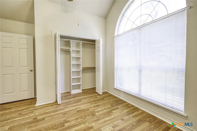 unfurnished bedroom featuring baseboards, light wood-style floors, a closet, and multiple windows