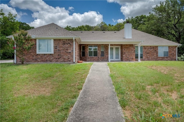 ranch-style home featuring brick siding, french doors, a front lawn, and a chimney