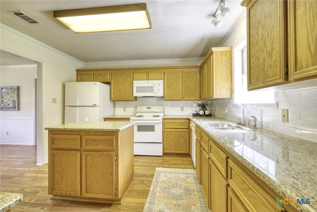 kitchen featuring white appliances, crown molding, a kitchen island, visible vents, and a sink