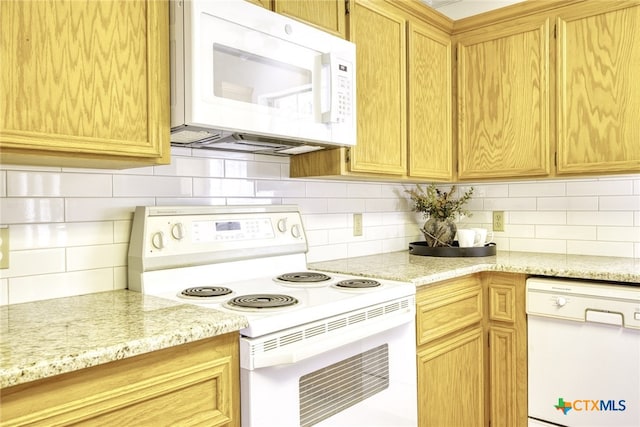 kitchen with white appliances, backsplash, and light stone counters