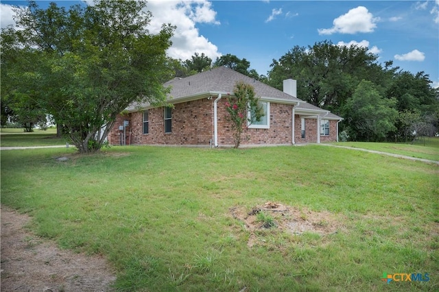 view of side of home with brick siding, a lawn, and a chimney