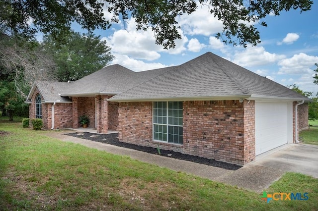 view of side of home with a lawn, brick siding, driveway, and an attached garage