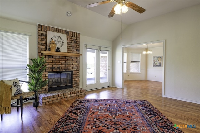 living area with baseboards, wood finished floors, vaulted ceiling, and a fireplace