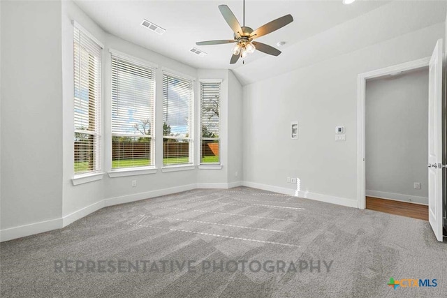 spare room featuring carpet floors, baseboards, ceiling fan, and visible vents