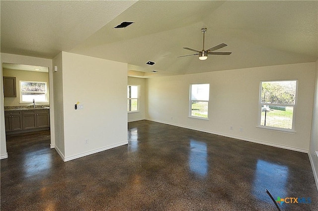 unfurnished room featuring vaulted ceiling, plenty of natural light, and a textured ceiling