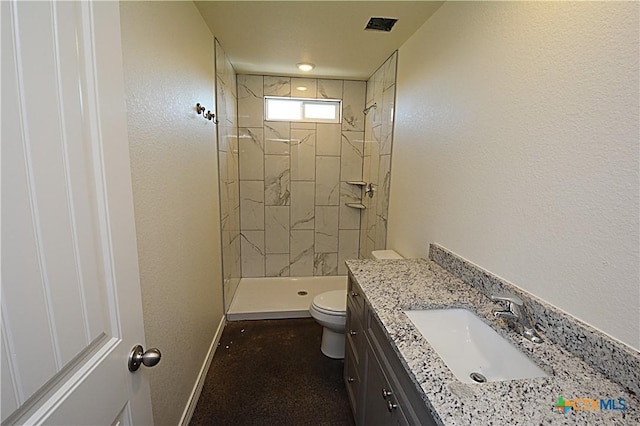 bathroom with toilet, vanity, and tiled shower